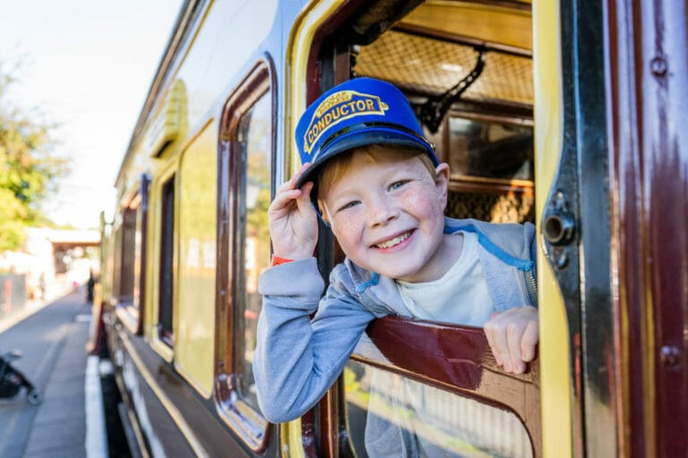 Smiling child on train with conductor hat